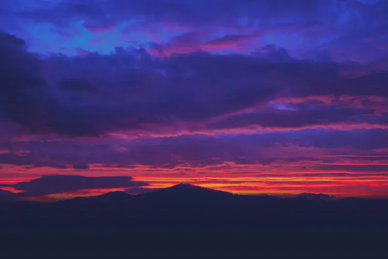 A vivid cloudy sunrise with deep purples, oranges, and blues